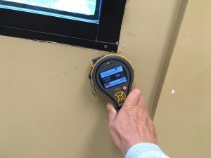 A person holds a mold detector against a wall