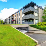 apartment building with grassy field in front and driveway