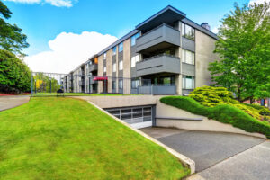 apartment building with grassy field in front and driveway